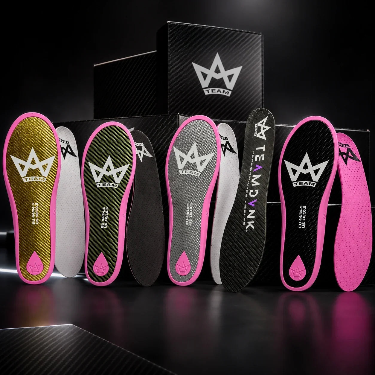 Performance insoles with pink edges, carbon fiber texture, and TEAM logo, displayed with branded boxes
